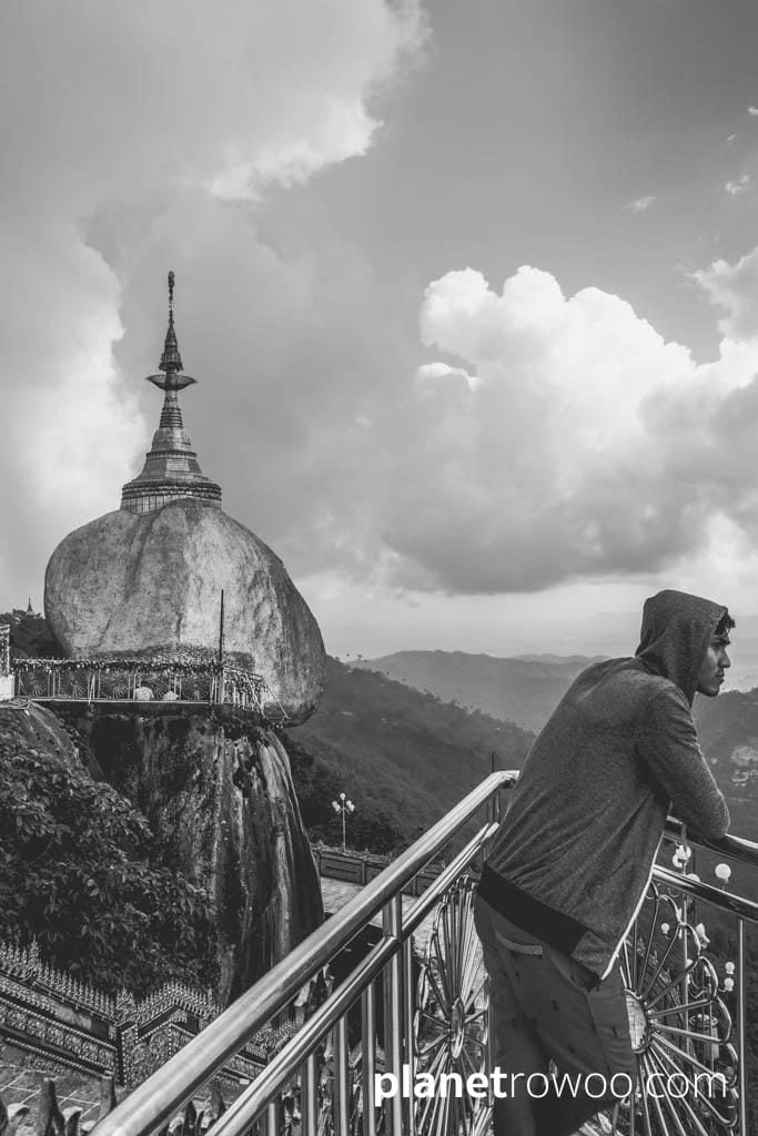 A young man looks out over the Kyaiktiyo mountain range with the Golden Rock in the background