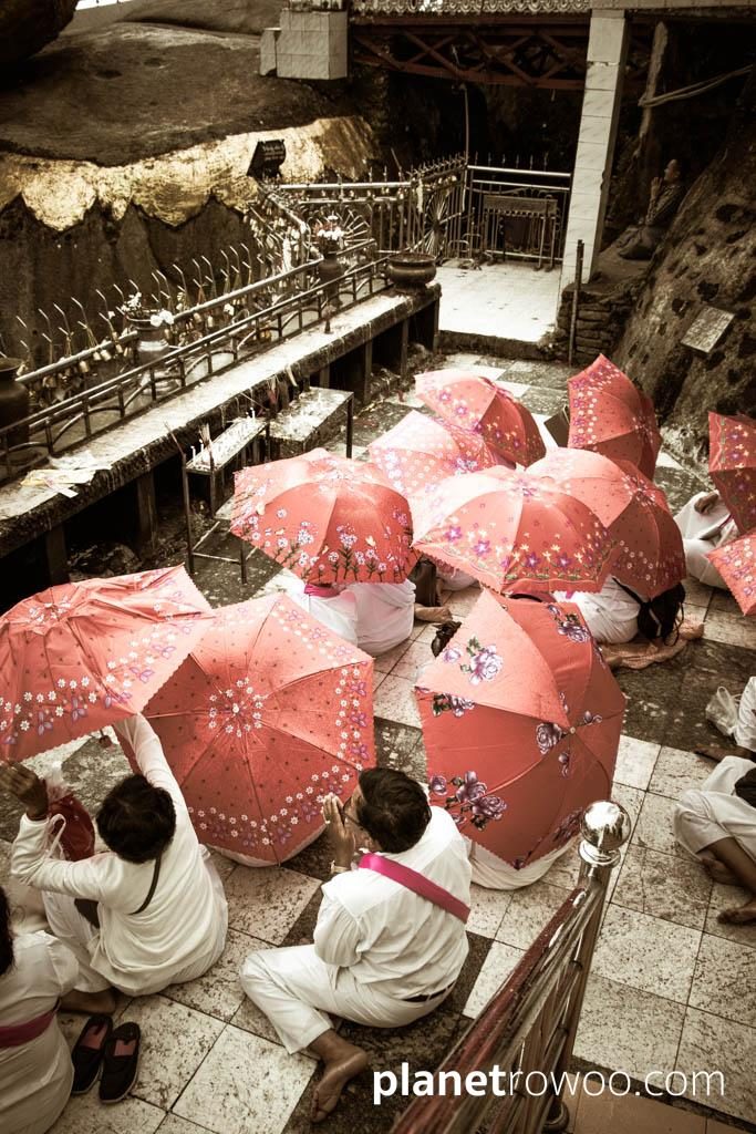 Cambodian pilgrims pay their respects in the rain at the Golden Rock