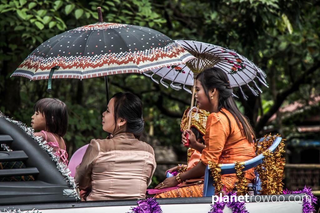 Burmese ladies in traditional dress ride to a Shinbyu ceremony
