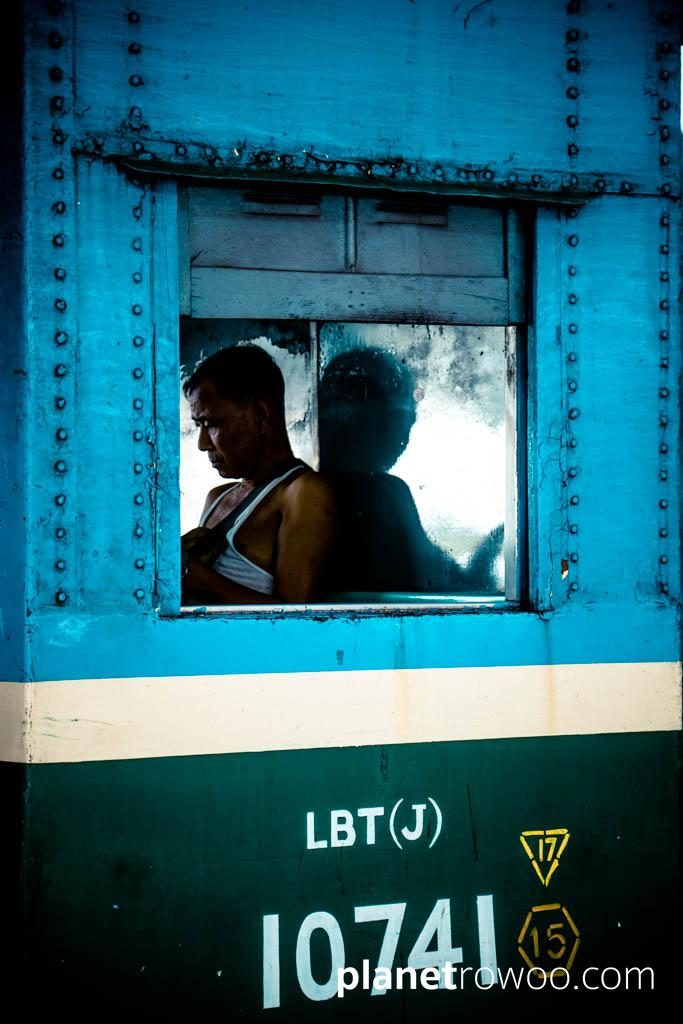 A traveller, through carriage window, Yangon Central station