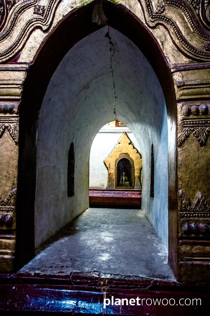 Passageway between the Ananda temple interior corridors with enshrined Buddha image visible in niche