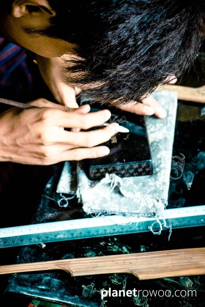Lacquerware artist etches a traditional design with a needle in a Bagan lacquerware workshop