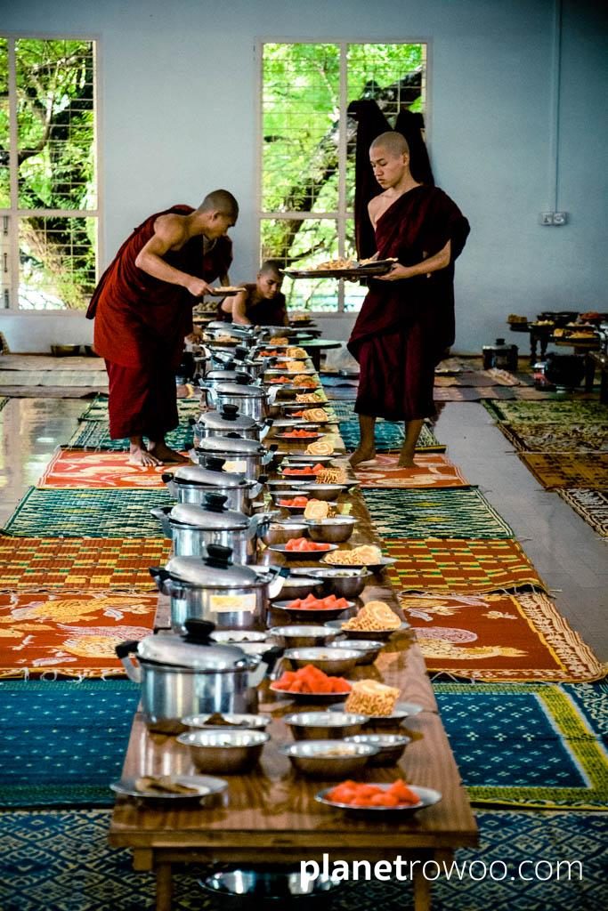 Novice monks prepare tables in Mandalay monastery dining hall